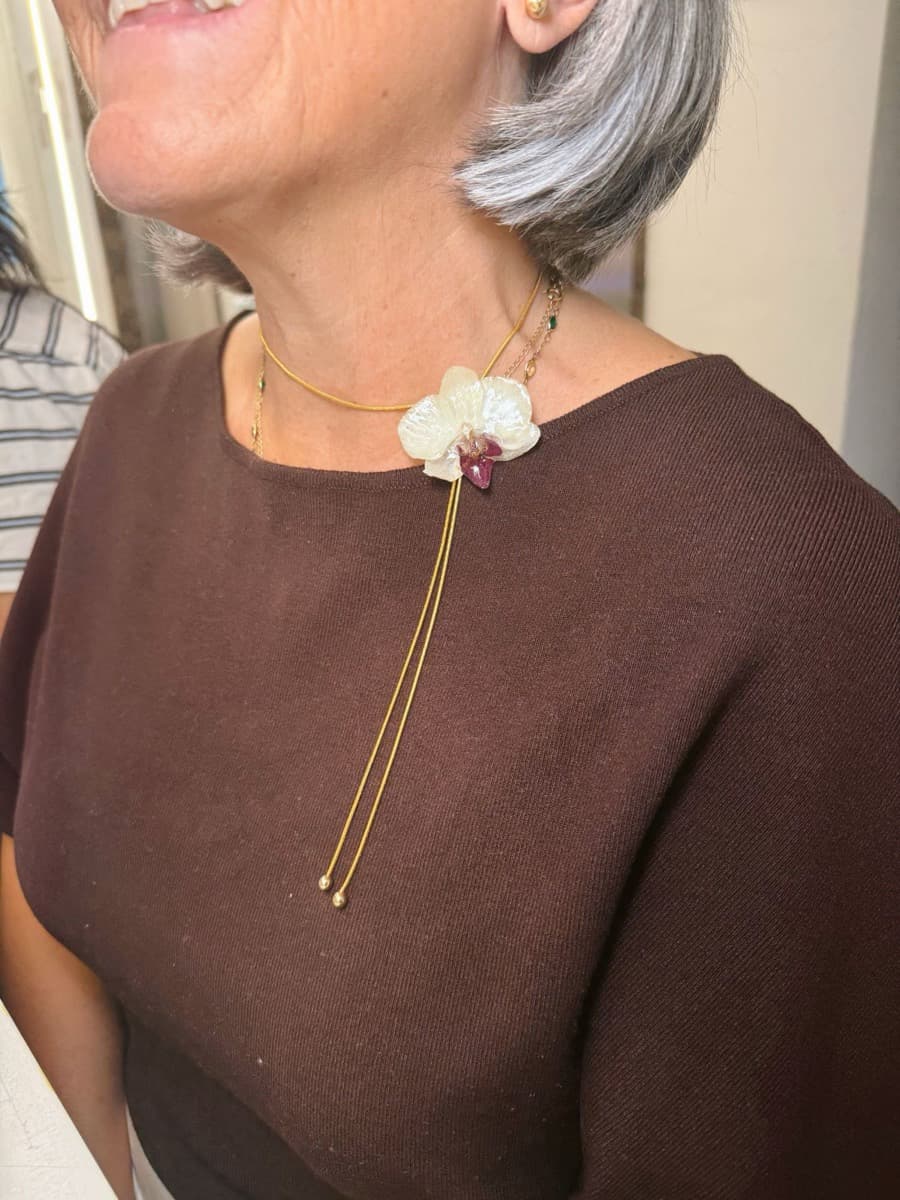 Collar con una orquídea blanca y centro morado en resina